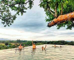 Un grupo de personas en una piscina natural rodeada de árboles y un paisaje montañoso.