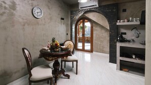 Un comedor con una mesa redonda, sillas y un reloj en la pared.