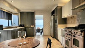 A modern kitchen with a dining area, large windows, and a view of the ocean. - Arthurs Holiday Villa (Arthurs Seat)