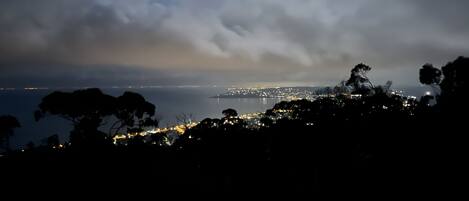 Une vue nocturne d’une ville côtière, avec la mer et les lumières de la ville en arrière-plan.