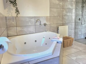 A bathroom with a large bathtub, a shower area, and a radiator. - Arthurs Holiday Villa (Arthurs Seat)