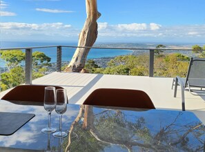 A table with two wine glasses and a view of the ocean and cityscape. - Arthurs Holiday Villa (Arthurs Seat)