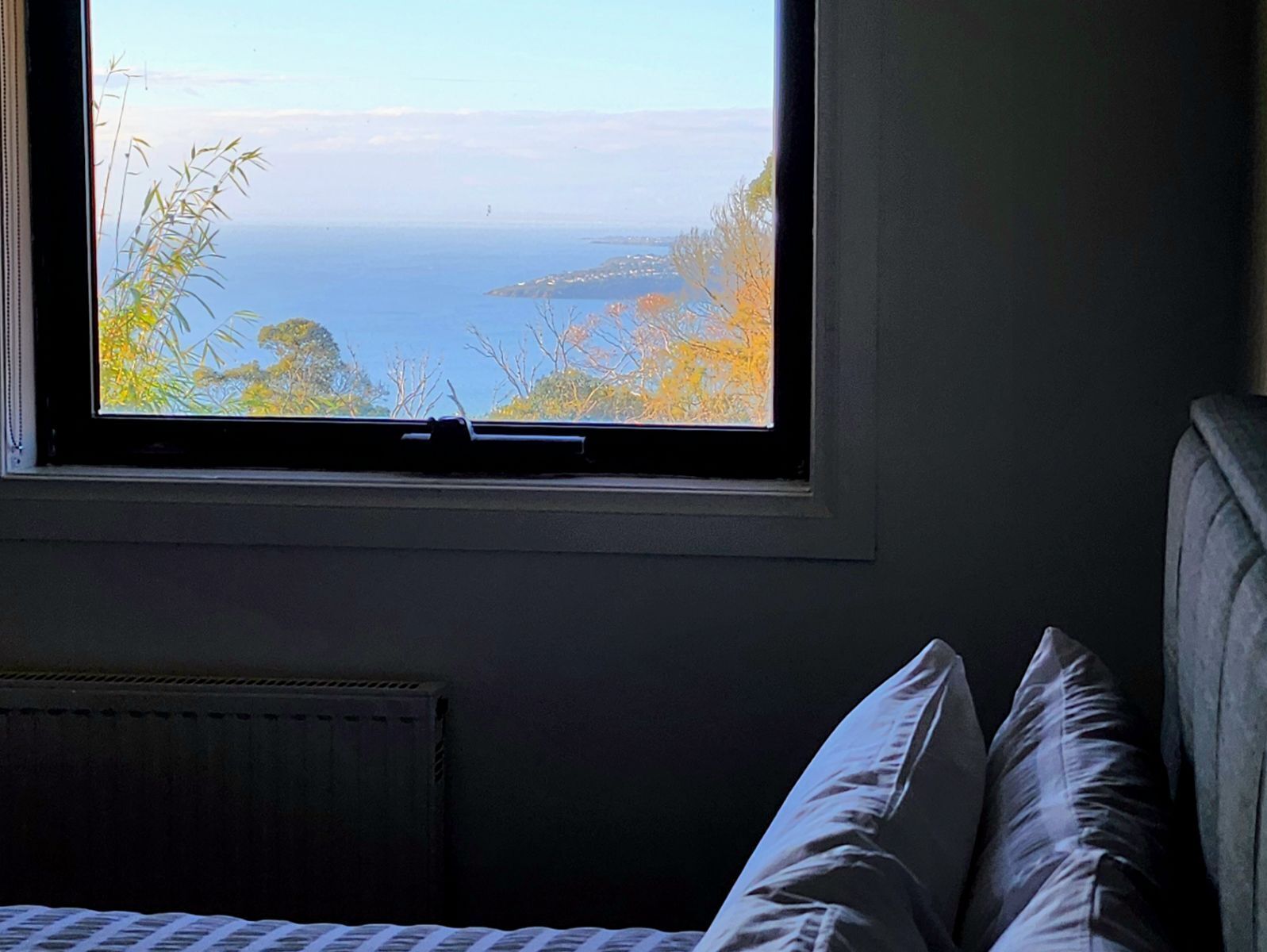 A bedroom with a window overlooking a coastal view.