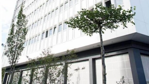 Moderni korkea kerrostalo, jossa on ruudukkomainen julkisivu, jossa on ikkunoita ja parvekkeita.