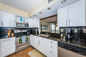 A modern kitchen with white cabinets, a microwave, stove, and a dishwasher.