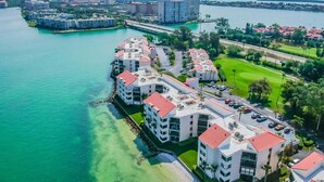 Un hotel costero con varias construcciones, un puerto deportivo y un puente al fondo.