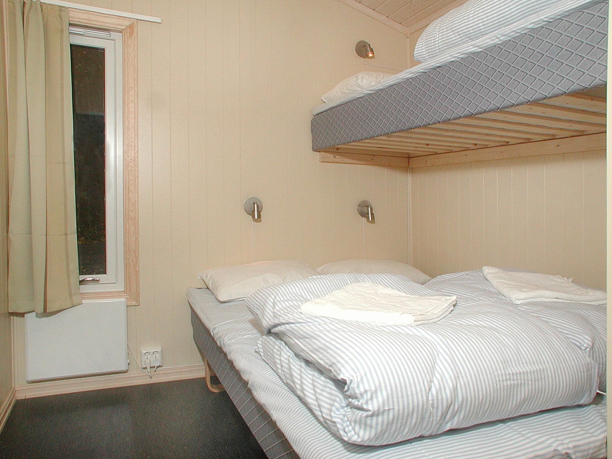 A room with two bunk beds, a window with curtains, and a wall-mounted light fixture.