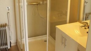 A bathroom with a glass-enclosed shower, a white sink, and a mirror.