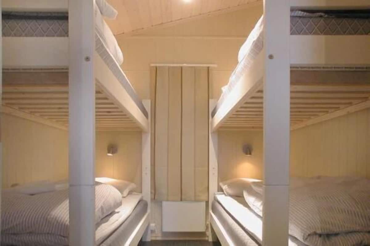 A bunk bed room with a central divider and two bedside lamps.