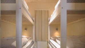A bunk bed room with a central divider and two bedside lamps.