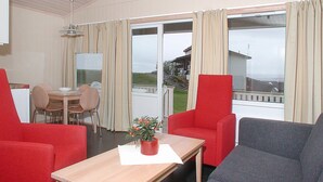 A room with a dining table, chairs, a red sofa, a grey sofa, and a potted plant. - Hedmarktoppen (Hamar)
