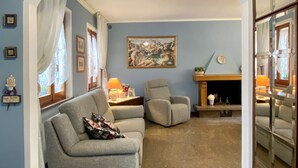 A living room with a grey sofa, a chair, a fireplace, and a large painting on the wall. - An exclusive terraced house in a very central position, 600 meters from the sea. (San Benedetto del Tronto)