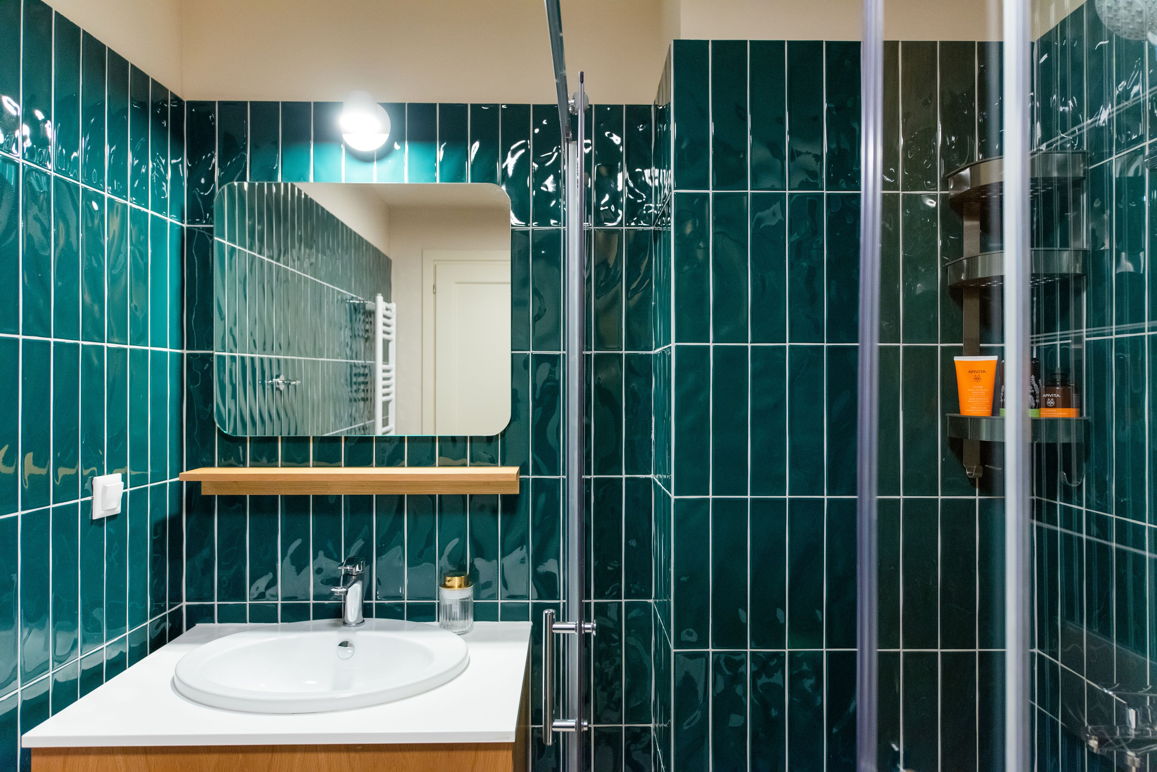 A modern bathroom with a white sink, a mirror, and a glass shower enclosure.