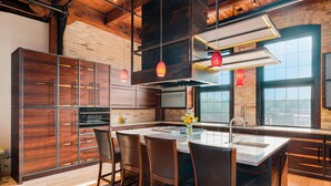 A modern kitchen with a large island, wooden cabinets, and pendant lighting. - 🌆One-of-a-Kind Downtown TC Penthouse | Luxe Design + Walk to Bay, Dining, Shops & Events ➠ 400W (Traverse City)