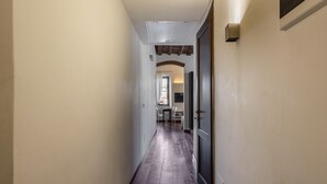 Un pasillo estrecho con suelo de madera, una puerta a la derecha y un ventanal al final.
