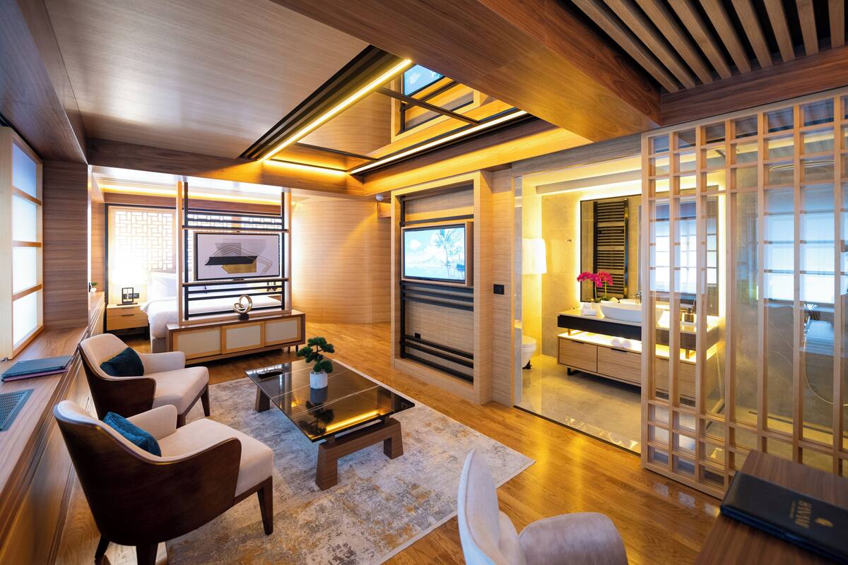 A modern living room with a fireplace, comfortable seating, and a view through a wooden screen.