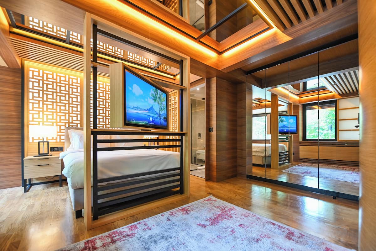 A modern hotel room with a wooden bed, a TV, and a view of the outdoors.