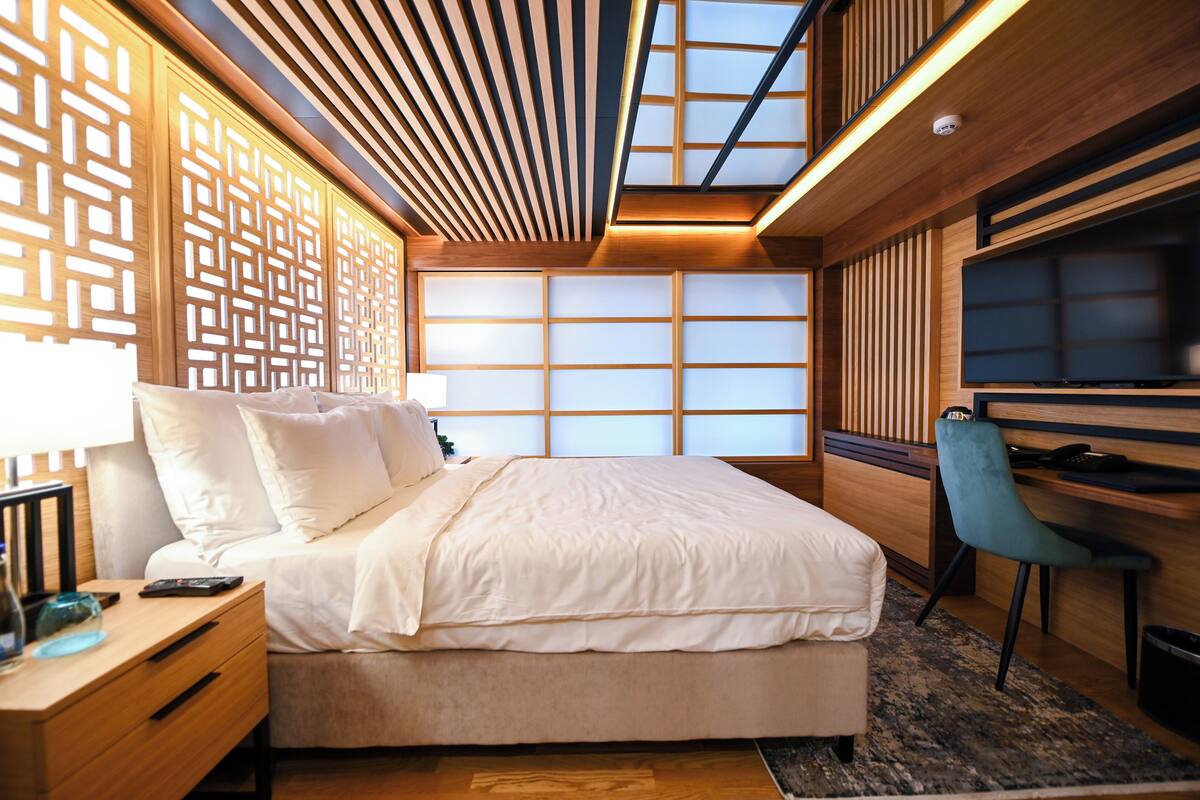 A modern bedroom with a large bed, a desk, and a chair.