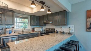 A modern kitchen with granite countertops, dark cabinetry, and a bar stool area. - Bent Creek 11 at Rumbling Bald (Lake Lure)
