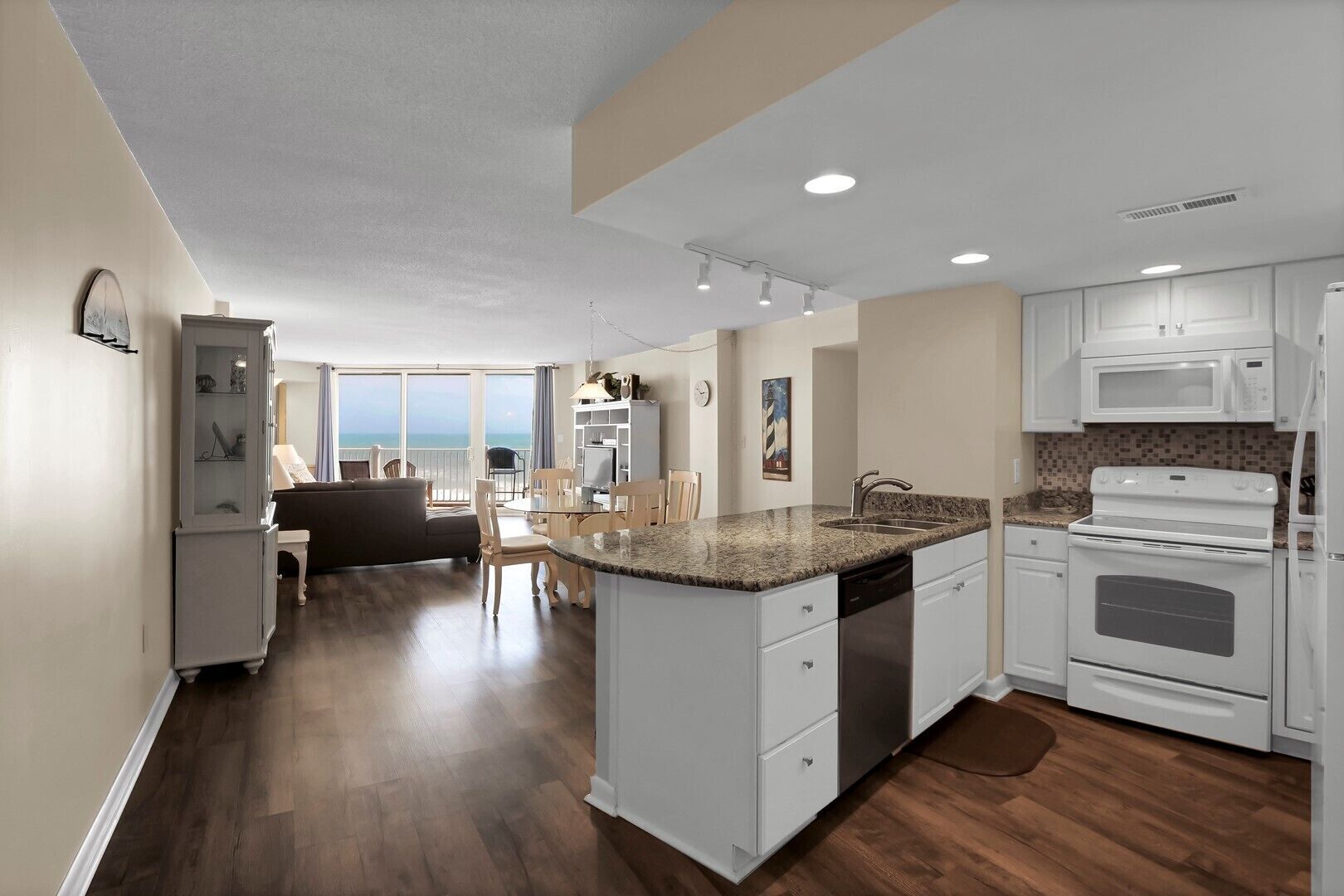 A modern kitchen with white cabinets, a granite countertop, and stainless steel appliances.