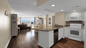 A modern kitchen with white cabinets, a granite countertop, and stainless steel appliances. - Oceanfront Point Unit with 3 Bedrooms and Great Oceanviews (North Topsail Beach)