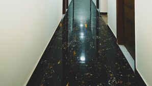 Un largo y estrecho pasillo con piso negro brillante y paredes blancas.