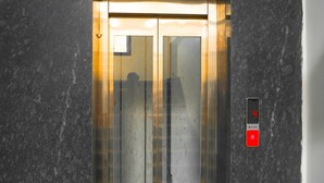 Un ascensor con pantalla digital que muestra el número 4, un botón rojo y una puerta de cristal.