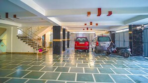 Amplio estacionamiento interior con suelo de baldosas, una escalera y un coche rojo estacionado en el centro.