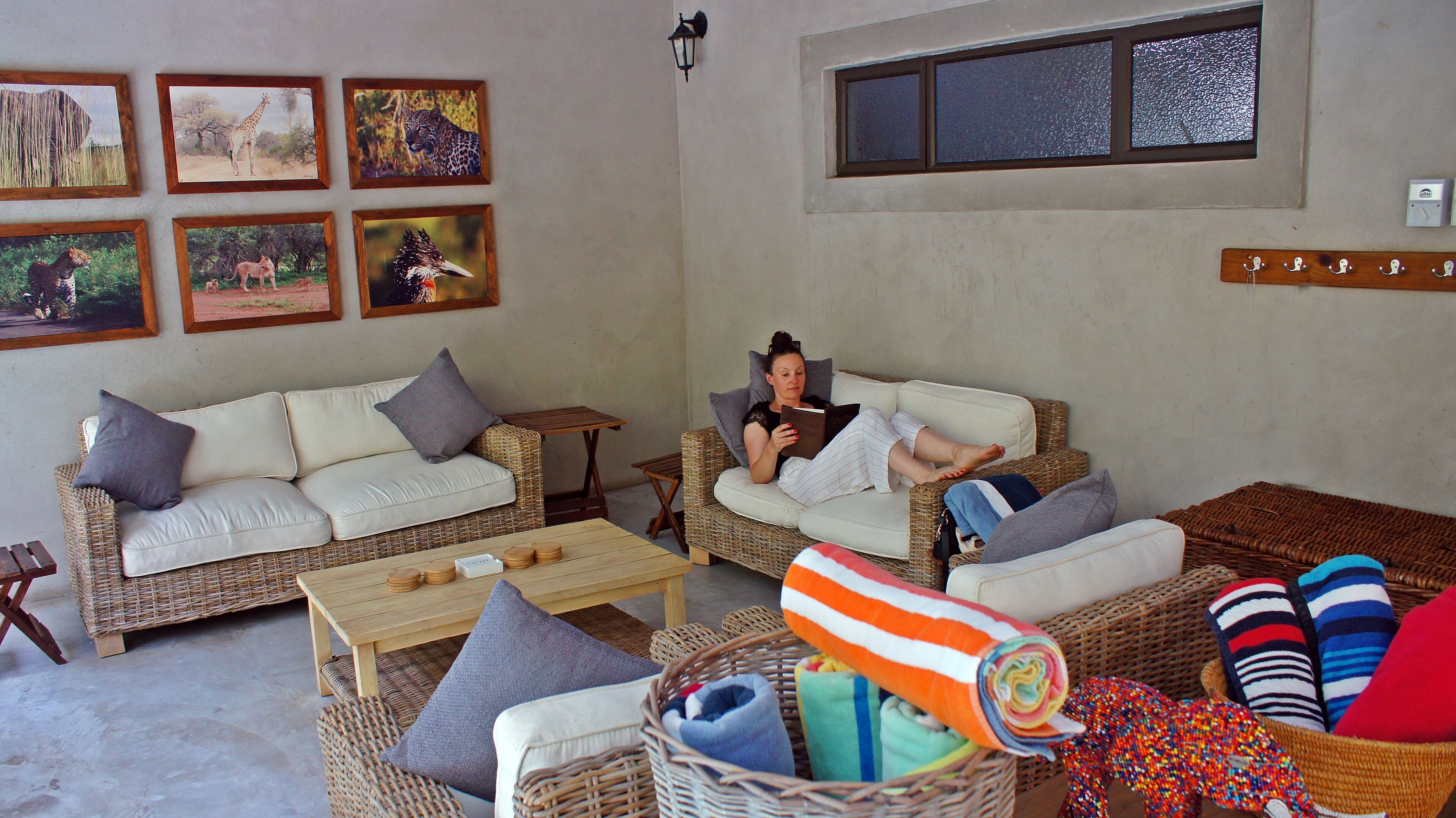 A living room with wicker furniture, a sofa, a coffee table, and a wall with framed animal pictures.