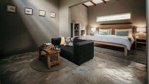 A modern bedroom with a large bed, a small sofa, a wooden side table, and a round rug. - Dream of Africa Bush Lodge (Nkomazi)