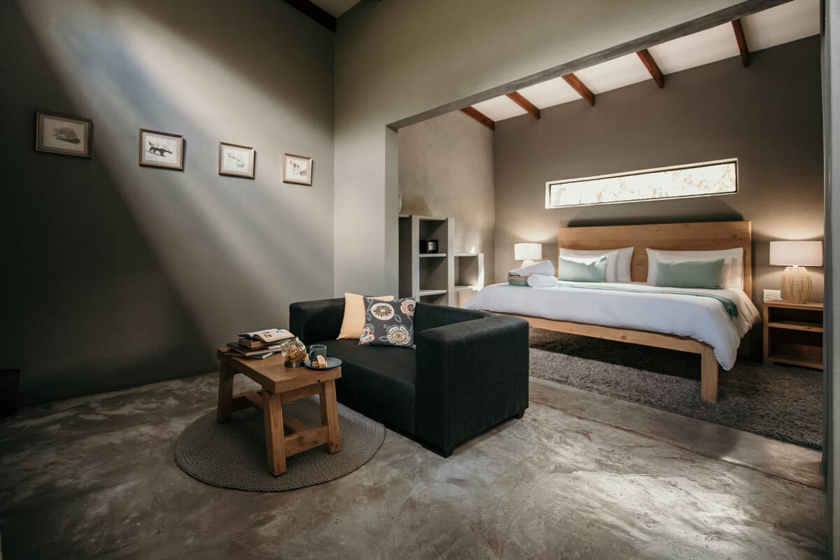 Ein modernes Schlafzimmer mit einem großen Bett, einer kleinen Couch, einem Holztischchen und einem runden Teppich.