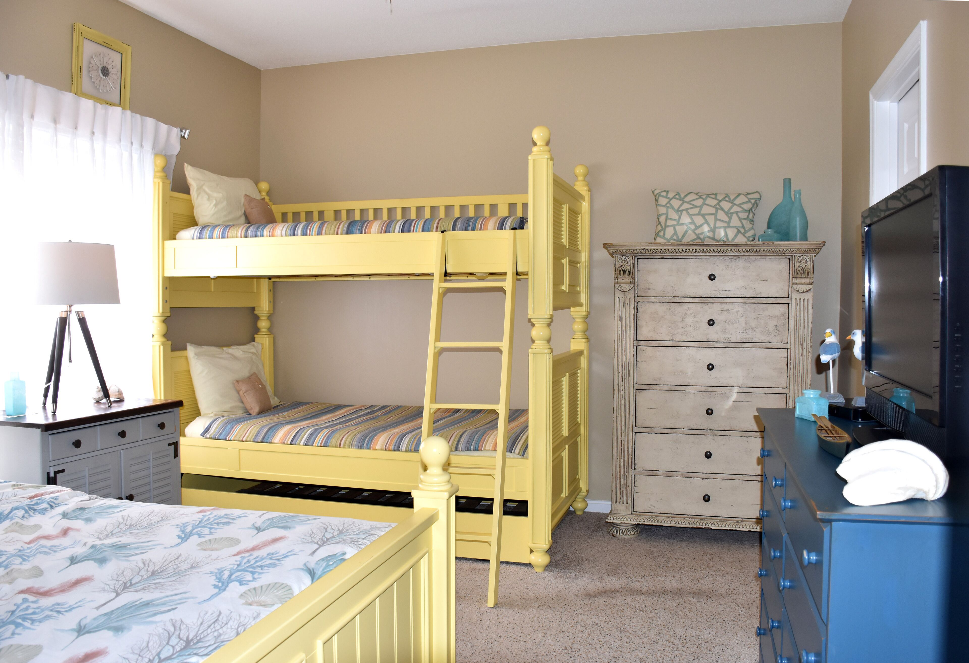 Une chambre à coucher avec un lit superposé, une commode, un bureau avec une lampe et un téléviseur.