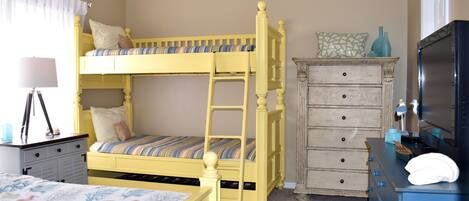 Une chambre à coucher avec un lit superposé, une commode, un bureau avec une lampe et un téléviseur.