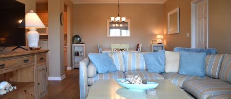A living room with a sofa, a coffee table, a TV, and a lamp.