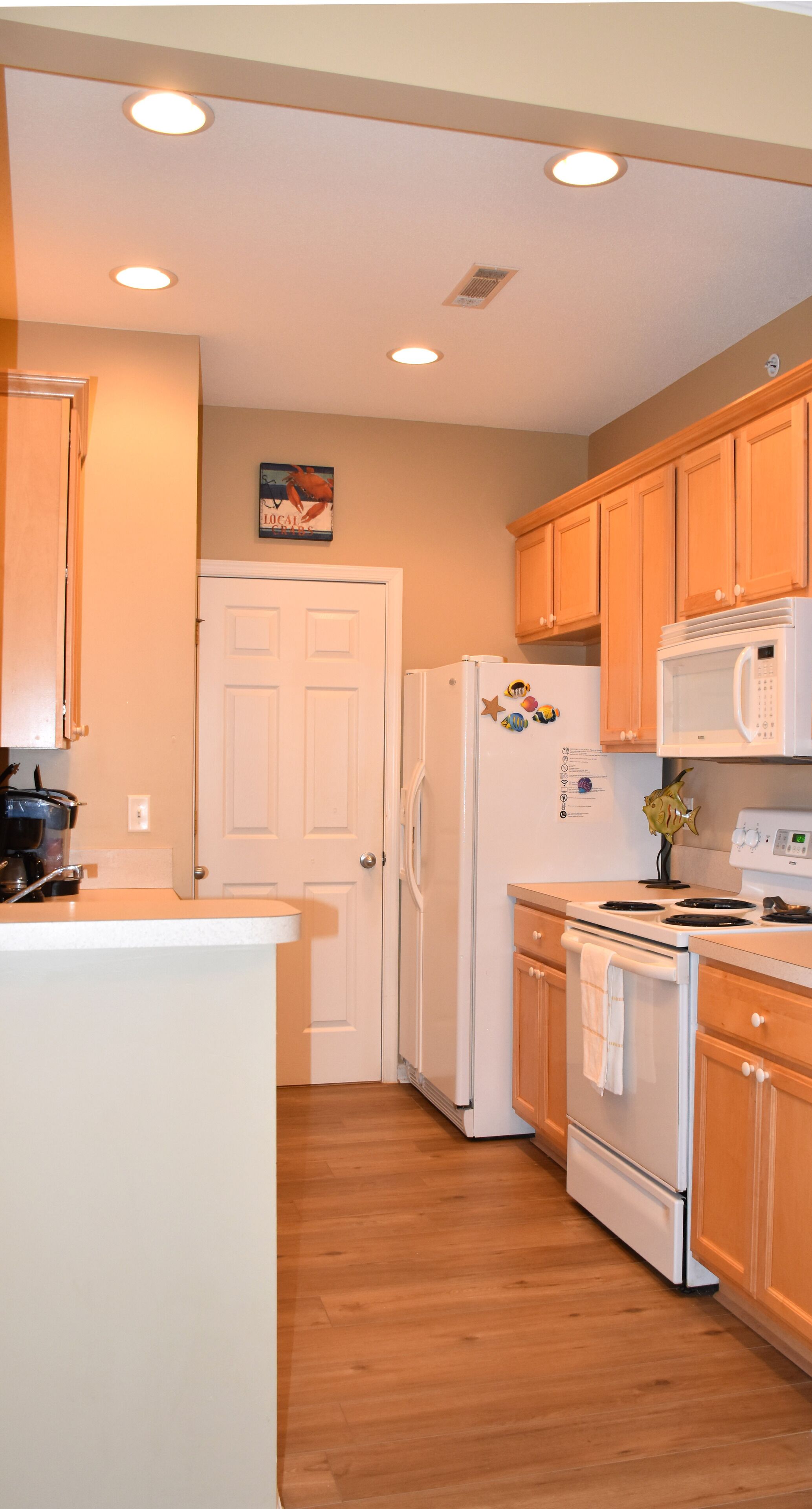 A kitchen with wooden cabinets, a white refrigerator, a microwave, and a stove.