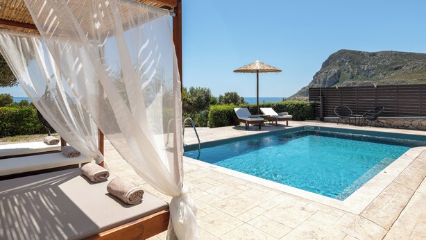 Ein Swimmingpool mit Liegestühlen, eine Pergola mit Dach und Blick aufs Meer.
