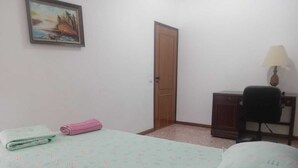 Un dormitori amb un llit, un escriptori, una cadira, una porta i un quadre a la paret.