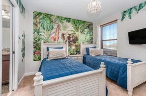 Une chambre avec deux lits, une fresque représentant des animaux de la jungle, une télévision et une fenêtre donnant sur un beau paysage.