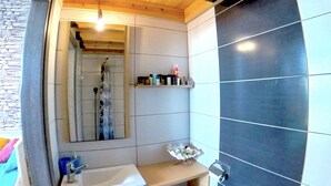 A bathroom with a wooden ceiling, a white sink, a toilet, and a mirror. - Beach Shack Studio s&l (Rhodes)