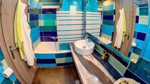 A bathroom with a bathtub, a sink, and a toilet. There are towels hanging on the wall and a mirror above the sink. - Deluxe Beach Apartment- Sleeps 2 & Private Terrace (Rhodes)