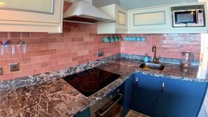 A kitchen with a granite countertop, a built-in oven, and a microwave. - Deluxe Beach Apartment- Sleeps 2 & Private Terrace (Rhodes)