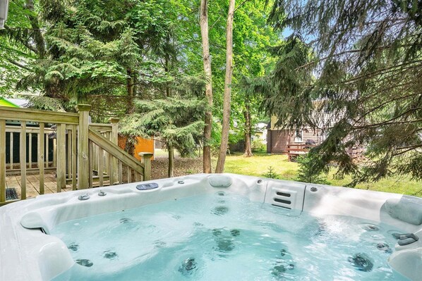 Ein Whirlpool im Garten mit einer Holzterrasse und einem Haus im Hintergrund.