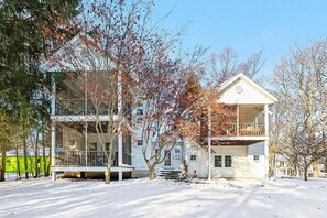 Ein zweigeschossiges Haus mit Balkon, umgeben von Bäumen und bedeckt mit Schnee.