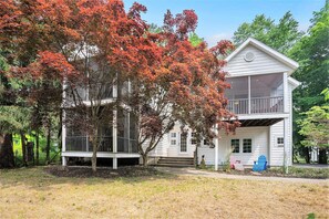 A two-story house with a balcony, a porch, and a small garden area.