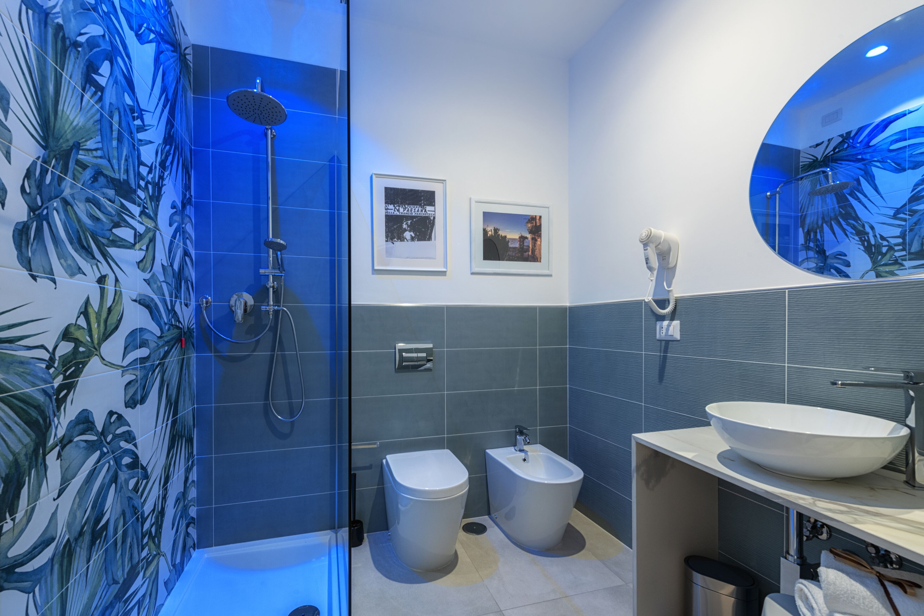 A modern bathroom with a glass-enclosed shower, a bidet, a large sink, and a mirror.