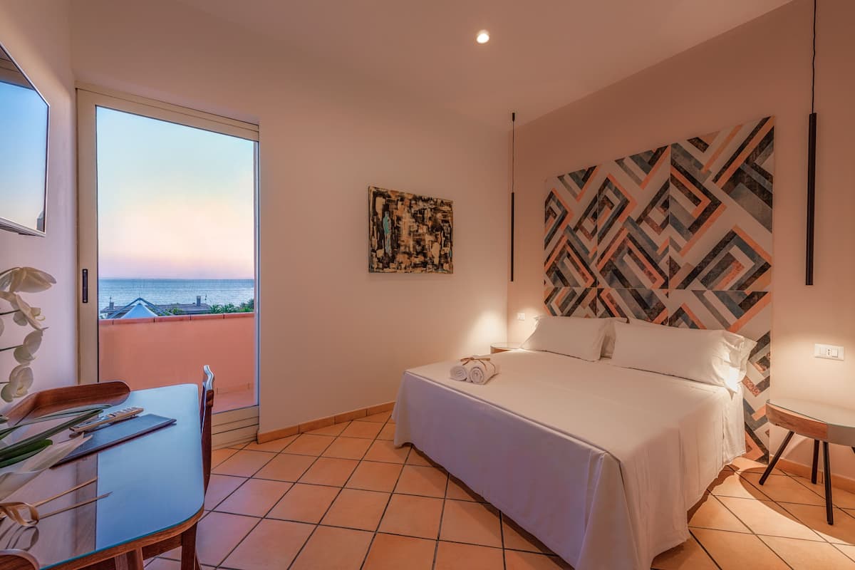 Un dormitorio con cama, escritorio y vista al mar.