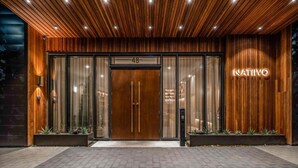 Un bâtiment moderne avec une façade en bois, une grande entrée vitrée et le nom « NATIVO » illuminé sur le côté droit.