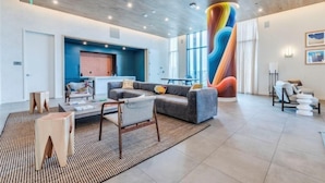 Un salon moderne avec un grand canapé, une table basse et une fresque murale colorée et originale.