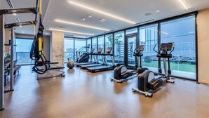 Une salle de sport moderne équipée de tapis de course, de vélos elliptiques et d’un appareil d’entraînement en suspension.