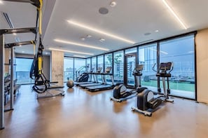 Un gimnasio moderno con cintas de correr, elípticas y un entrenador de suspensión.